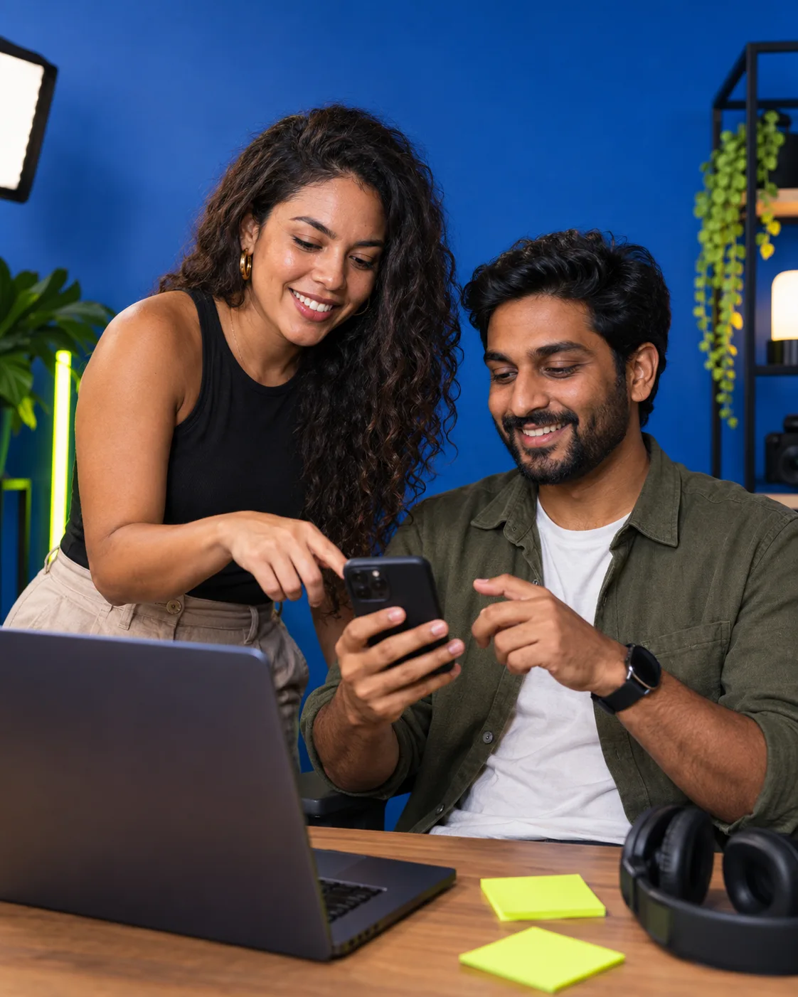 Two creators discussing content on a smartphone in a studio